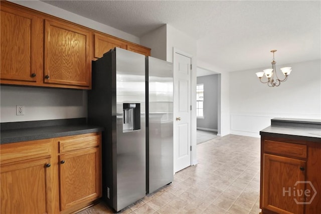15 Springwater Dr, Port Wentworth, GA 31407 - kitchen with stainless steel fridge with ice dispenser, dark countertops, brown cabinetry, a chandelier, and pendant lighting