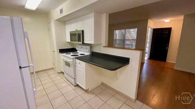 401 N Cromwell Rd Unit G1, Savannah, GA 31410 - kitchen with white appliances, white cabinetry, dark countertops, and light tile patterned floors
