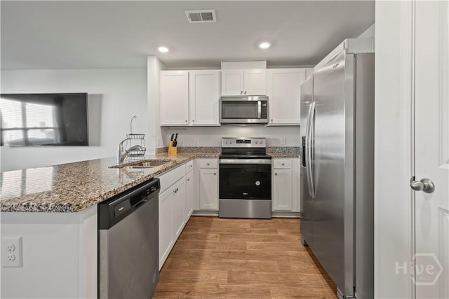 206 Coneflower Rd, Bloomingdale, GA 31302 - kitchen with stainless steel appliances, a peninsula, light wood finished floors, white cabinets, and light stone counters