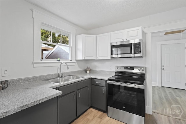 1122 SE 36th St, Savannah, GA 31404 - kitchen with stainless steel appliances, light wood finished floors, white cabinets, light countertops, and a textured ceiling