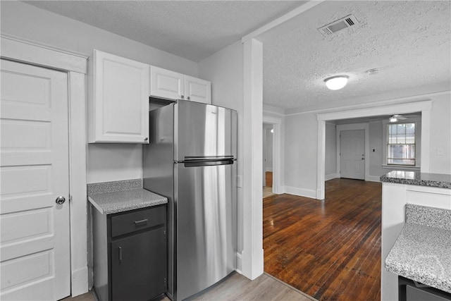 1122 SE 36th St, Savannah, GA 31404 - kitchen featuring freestanding refrigerator, white cabinetry, dark wood-type flooring, light stone counters, and a textured ceiling