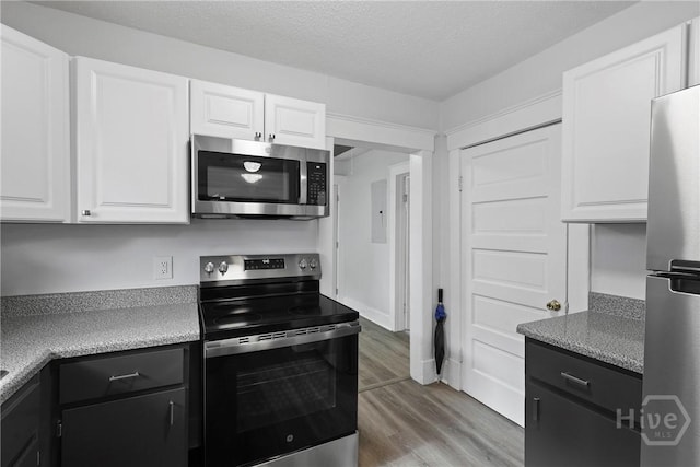 1122 SE 36th St, Savannah, GA 31404 - kitchen with stainless steel appliances, dark cabinetry, white cabinetry, light wood-style floors, and a textured ceiling