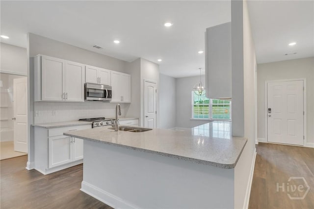102 Simon Cir, Guyton, GA 31312 - kitchen with stainless steel microwave, dark wood finished floors, tasteful backsplash, light stone countertops, and recessed lighting