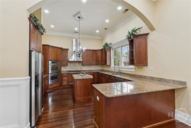 45 Shore Rd, Savannah, GA 31419 - kitchen featuring wall chimney exhaust hood, appliances with stainless steel finishes, a peninsula, a kitchen island with sink, and arched walkways