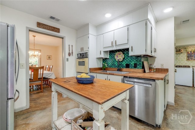 7012 Sandnettles Dr, Savannah, GA 31410 - kitchen featuring stainless steel appliances, concrete floors, washer / dryer, decorative backsplash, and a chandelier