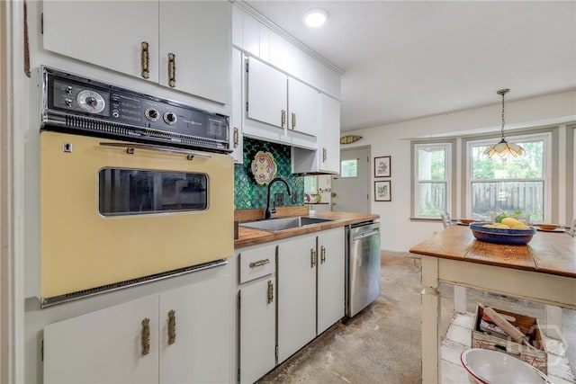 7012 Sandnettles Dr, Savannah, GA 31410 - kitchen with white oven, stainless steel dishwasher, concrete floors, white cabinets, and pendant lighting