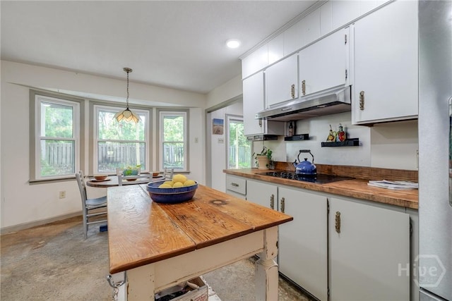 7012 Sandnettles Dr, Savannah, GA 31410 - kitchen with under cabinet range hood, butcher block countertops, white cabinets, black electric cooktop, and pendant lighting