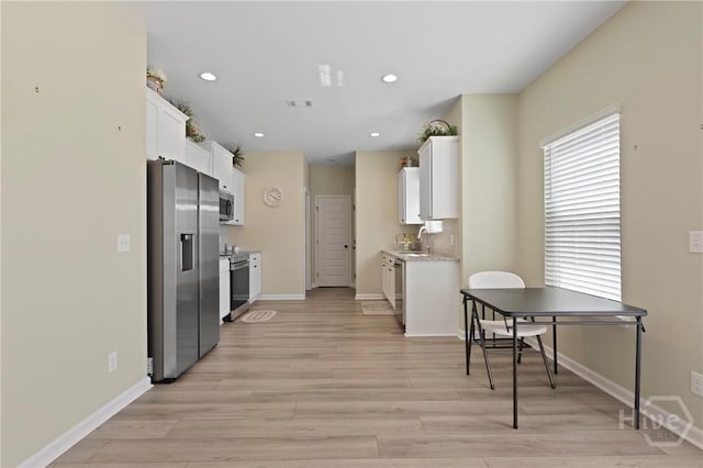 1447 Arnold Dr SE, Allenhurst, GA 31301 - kitchen featuring appliances with stainless steel finishes, white cabinetry, light wood-style flooring, and recessed lighting