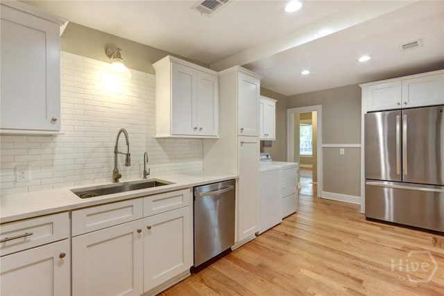 416 E 61st St, Savannah, GA 31405 - kitchen with stainless steel appliances, independent washer and dryer, white cabinetry, tasteful backsplash, and light countertops