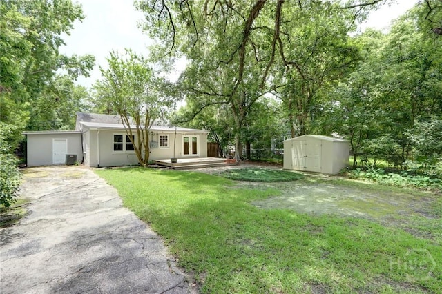 416 E 61st St, Savannah, GA 31405 - view of grassy yard featuring a storage shed, a deck, driveway, and view of scattered trees