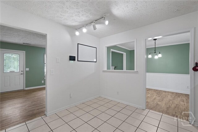 75 Brown Thrasher Ct, Richmond Hill, GA 31324 - empty room featuring a textured ceiling, light wood finished floors, a chandelier, rail lighting, and a wainscoted wall