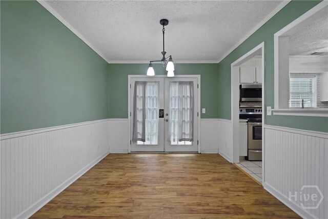 75 Brown Thrasher Ct, Richmond Hill, GA 31324 - unfurnished dining area with a textured ceiling, a wainscoted wall, wood finished floors, ornamental molding, and french doors