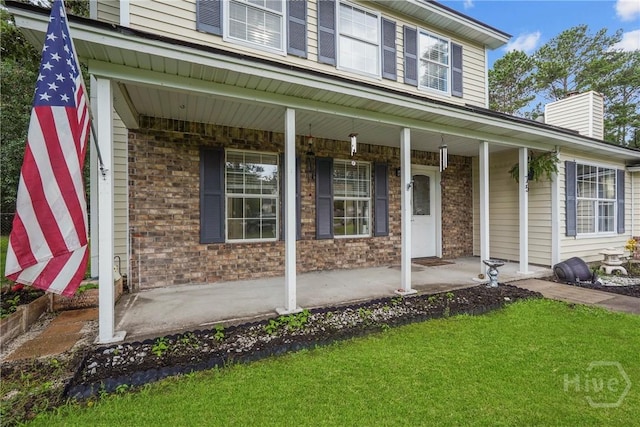 75 Brown Thrasher Ct, Richmond Hill, GA 31324 - view of exterior entry with covered porch, brick siding, and a chimney