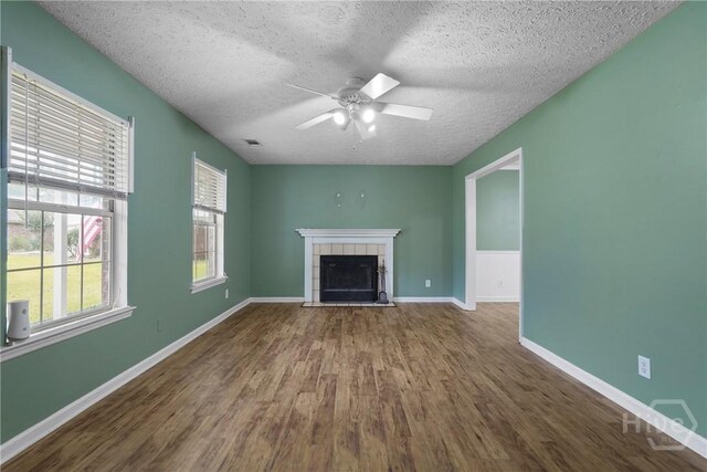 75 Brown Thrasher Ct, Richmond Hill, GA 31324 - unfurnished living room with a textured ceiling, wood finished floors, a ceiling fan, and a tile fireplace