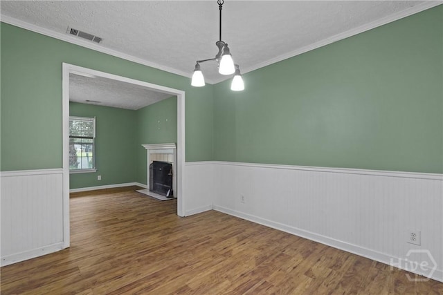75 Brown Thrasher Ct, Richmond Hill, GA 31324 - unfurnished living room with wainscoting, a textured ceiling, wood finished floors, a fireplace, and ornamental molding
