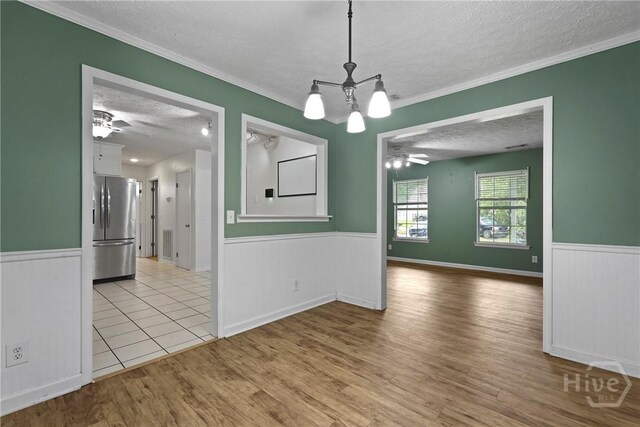 75 Brown Thrasher Ct, Richmond Hill, GA 31324 - unfurnished dining area with a textured ceiling, a ceiling fan, wainscoting, wood finished floors, and a chandelier