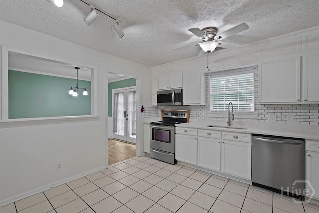 75 Brown Thrasher Ct, Richmond Hill, GA 31324 - kitchen featuring appliances with stainless steel finishes, tasteful backsplash, light countertops, white cabinetry, and a textured ceiling