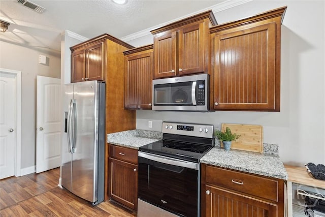 112 Kingsley Dr N, Guyton, GA 31312 - kitchen featuring stainless steel appliances, wood finished floors, light stone countertops, crown molding, and brown cabinets