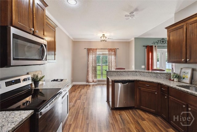 112 Kingsley Dr N, Guyton, GA 31312 - kitchen with appliances with stainless steel finishes, dark wood-style flooring, crown molding, light stone countertops, and a peninsula