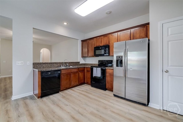 7 Hartland Ct, Savannah, GA 31407 - kitchen featuring black appliances, light wood-type flooring, dark stone counters, brown cabinets, and recessed lighting