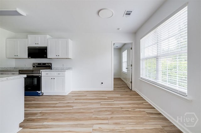 140 Abigail Cir, Ellabell, GA 31308 - kitchen with stainless steel electric range oven, black microwave, light wood finished floors, and white cabinetry