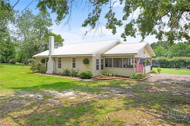 1072 Burtons Ferry Highway, Sylvania, GA 30467 - view of front facade with a chimney, a sunroom, a front yard, and a metal roof