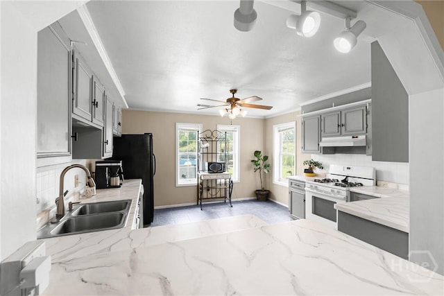 1072 Burtons Ferry Highway, Sylvania, GA 30467 - kitchen with white gas stove, gray cabinetry, under cabinet range hood, decorative backsplash, and light stone countertops