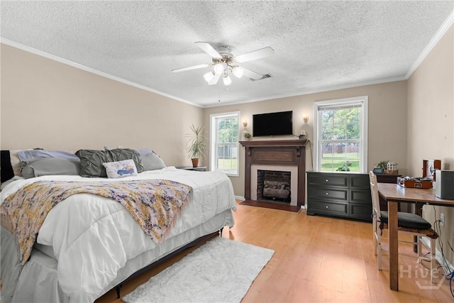 1072 Burtons Ferry Highway, Sylvania, GA 30467 - bedroom featuring light wood-type flooring, ornamental molding, a fireplace, a textured ceiling, and a ceiling fan