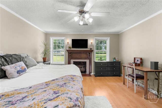 1072 Burtons Ferry Highway, Sylvania, GA 30467 - bedroom featuring a textured ceiling, multiple windows, light wood finished floors, ornamental molding, and a fireplace with flush hearth