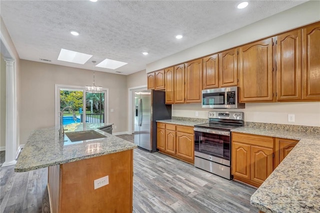 600 Old Louisville Rd, Guyton, GA 31312 - kitchen featuring appliances with stainless steel finishes, a skylight, light wood-type flooring, a kitchen island with sink, and recessed lighting