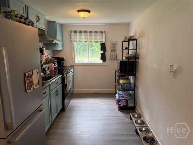 3052 Effingham Hwy, Sylvania, GA 30467 - kitchen featuring freestanding refrigerator, green cabinets, stainless steel range with electric stovetop, wall chimney range hood, and wood finished floors