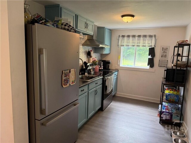 3052 Effingham Hwy, Sylvania, GA 30467 - kitchen with freestanding refrigerator, wall chimney exhaust hood, light wood-style flooring, green cabinets, and decorative backsplash