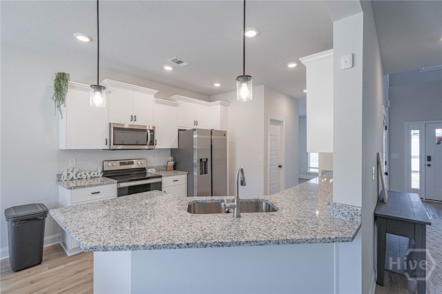 194 Gavin Way, Rincon, GA 31326 - kitchen with appliances with stainless steel finishes, a peninsula, light wood-type flooring, white cabinetry, and light stone countertops