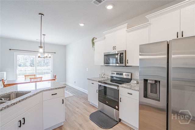 194 Gavin Way, Rincon, GA 31326 - kitchen with appliances with stainless steel finishes, white cabinets, light wood-style floors, light stone countertops, and pendant lighting