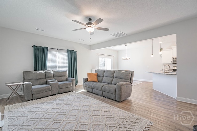 194 Gavin Way, Rincon, GA 31326 - living room with ceiling fan, light wood finished floors, a chandelier, and a textured ceiling