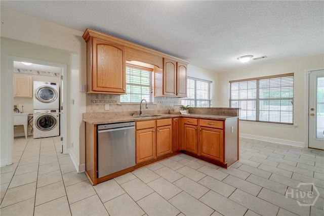 118 Plantation Way, Guyton, GA 31312 - kitchen with stainless steel dishwasher, stacked washing machine and dryer, a textured ceiling, light stone counters, and backsplash