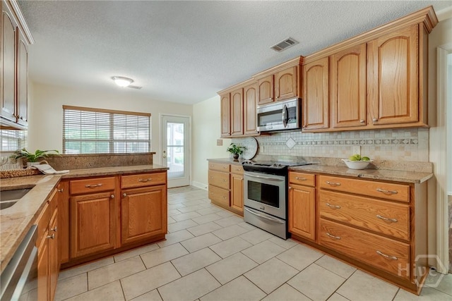 118 Plantation Way, Guyton, GA 31312 - kitchen with stainless steel appliances, a textured ceiling, healthy amount of natural light, tasteful backsplash, and a peninsula