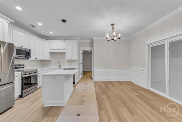 135 Houston St, Pooler, GA 31322 - kitchen featuring appliances with stainless steel finishes, a chandelier, light wood-type flooring, light countertops, and crown molding