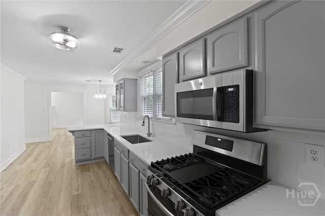 103 Olde Towne Rd, Savannah, GA 31410 - kitchen with stainless steel appliances, gray cabinetry, ornamental molding, backsplash, and a chandelier