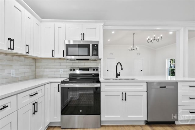 4630 Herty Dr, Savannah, GA 31405 - kitchen with appliances with stainless steel finishes, a chandelier, light countertops, backsplash, and white cabinets