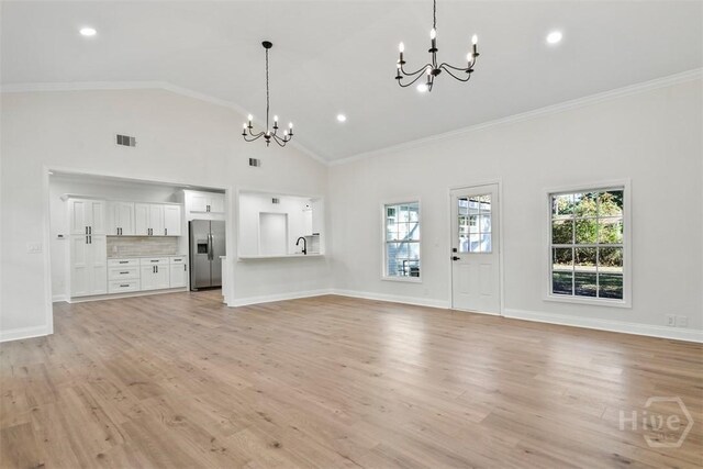 4630 Herty Dr, Savannah, GA 31405 - unfurnished living room with a chandelier, crown molding, light wood finished floors, high vaulted ceiling, and recessed lighting