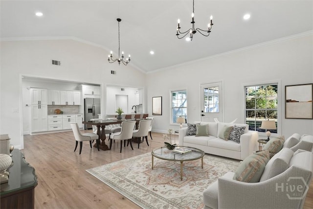 4630 Herty Dr, Savannah, GA 31405 - living area with a chandelier, plenty of natural light, light wood-style floors, ornamental molding, and high vaulted ceiling