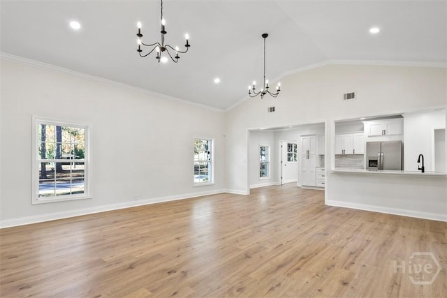 4630 Herty Dr, Savannah, GA 31405 - unfurnished living room with a chandelier, healthy amount of natural light, ornamental molding, high vaulted ceiling, and light wood-type flooring