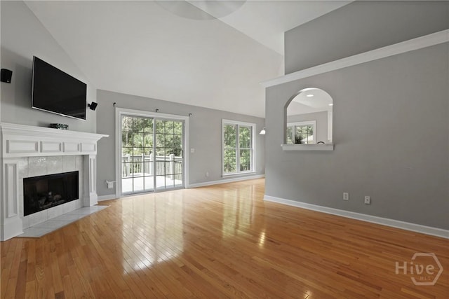 706 Southbridge Blvd, Savannah, GA 31405 - unfurnished living room featuring light wood-style floors, a tiled fireplace, high vaulted ceiling, and arched walkways