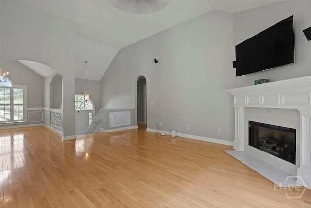 706 Southbridge Blvd, Savannah, GA 31405 - unfurnished living room with arched walkways, light wood-style floors, a fireplace with flush hearth, a wainscoted wall, and high vaulted ceiling