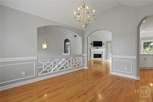 706 Southbridge Blvd, Savannah, GA 31405 - unfurnished dining area featuring light wood finished floors, vaulted ceiling, a fireplace, wainscoting, and a chandelier