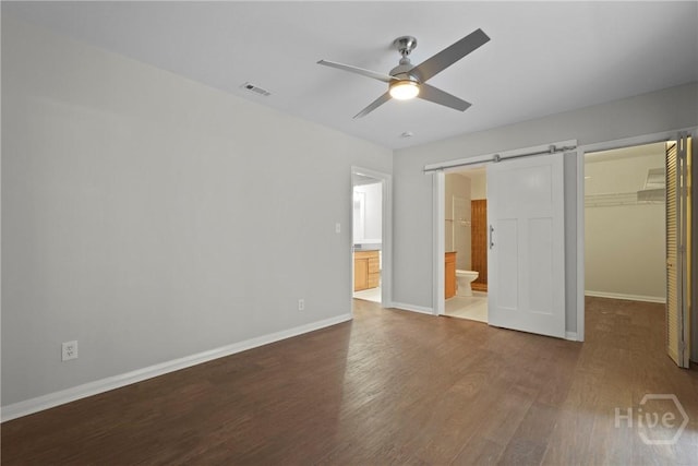 2133 Bacon Park Dr, Savannah, GA 31406 - unfurnished bedroom featuring a spacious closet, wood finished floors, a barn door, connected bathroom, and a closet