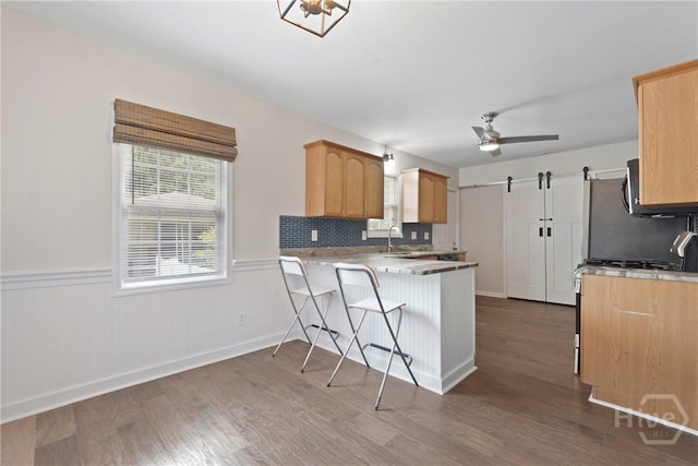 2133 Bacon Park Dr, Savannah, GA 31406 - kitchen with dark wood-style flooring, wainscoting, a peninsula, ceiling fan, and tasteful backsplash