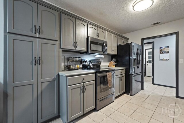 31 Pembroke Pl, Pembroke, GA 31321 - kitchen featuring appliances with stainless steel finishes, a textured ceiling, light countertops, light tile patterned flooring, and gray cabinetry