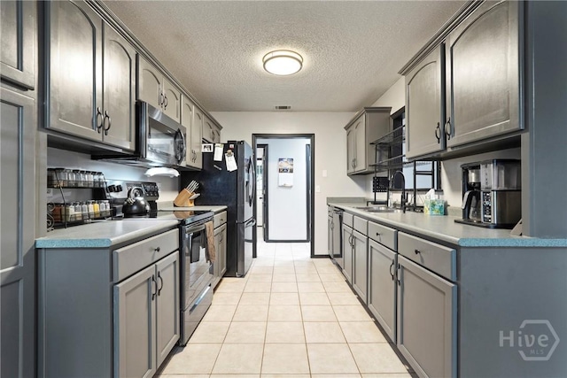 31 Pembroke Pl, Pembroke, GA 31321 - kitchen with appliances with stainless steel finishes, a textured ceiling, light tile patterned floors, light countertops, and gray cabinetry
